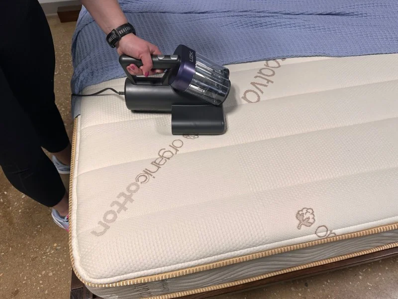 A person vacuuming a mattress with an UZK Bed Vacuum Cleaner.
