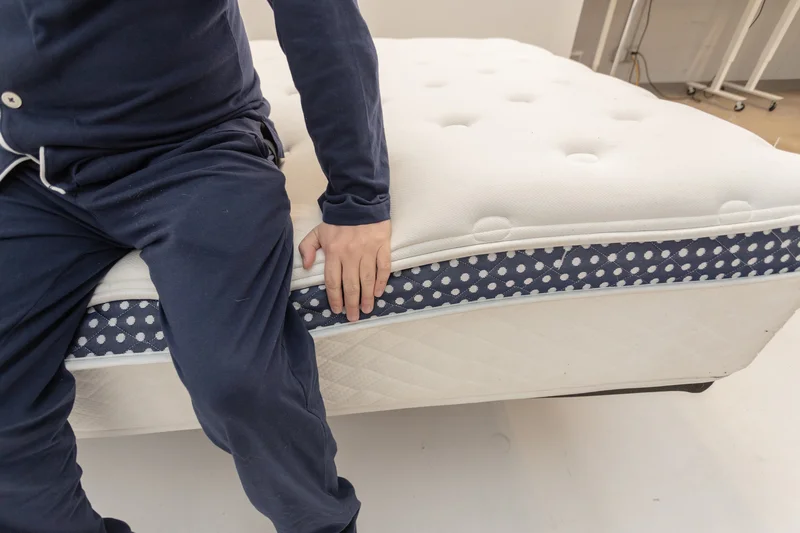A mattress tester assessing the edge support of the WinkBed Plus.