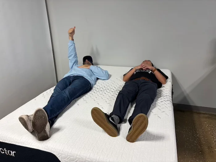 Two men lying on a Nectar Premier Memory Foam mattress. One of them is raising a thumb to indicate that he can feel his partner's movement.