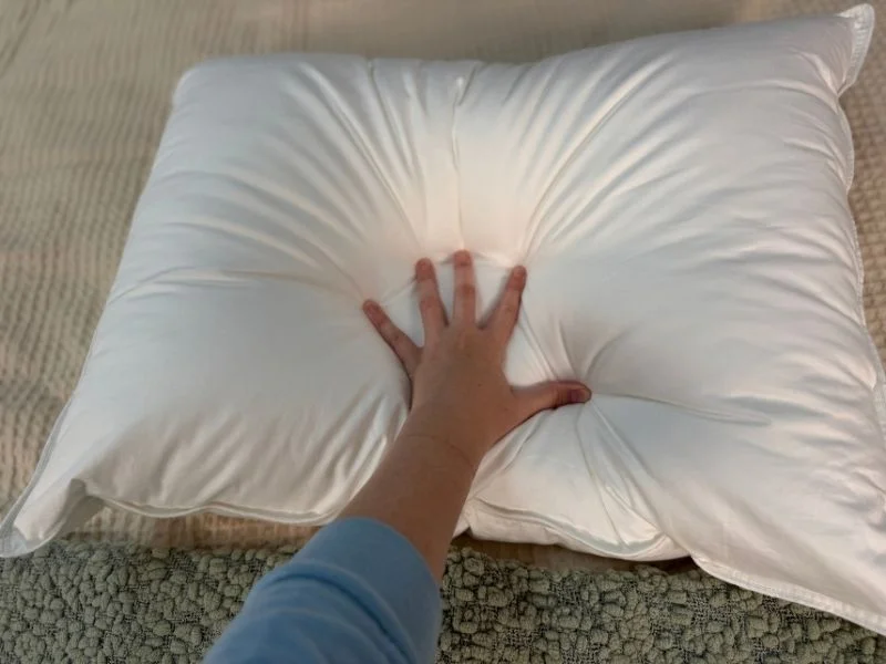 Our tester showing the compression of the Quince Down Alternative Pillow by pressing her hand down