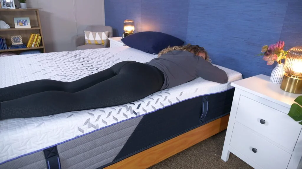 A woman lying on her stomach on the Nectar Luxe Hybrid mattress.