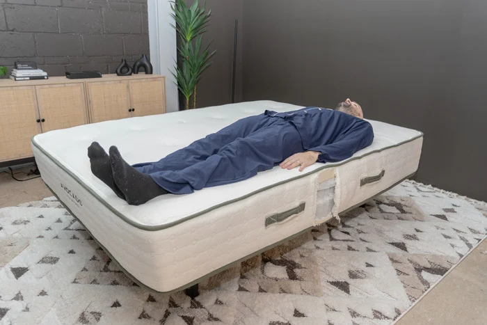 A man lying on his back on the Avocado Green mattress.