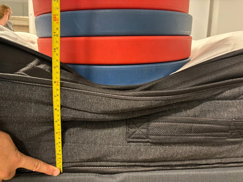 A mattress tester uses weighted plates to assess the edge support of the Nolah Evolution Comfort Plus.