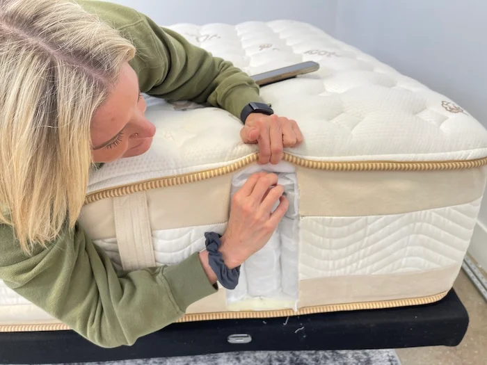 A woman cutting open the side of the Saatva Rx and looking at its layers.