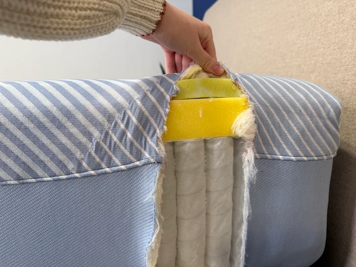 A closeup of the side of the Sealy Posturepedic mattress. The side has been cut open, revealing the layers of springs and foam underneath.