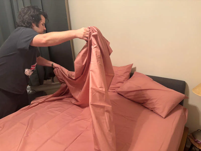Our product tester making a bed with Silk & Snow Cotton Percale Bed Sheets
