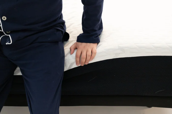 A close-up image of someone sitting on the edge of the Nectar mattress to test its edge support.