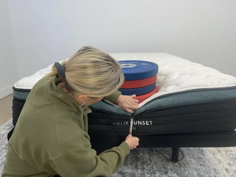 Our tester measuring weight plates on the edge of the Helix Sunset Luxe Mattress