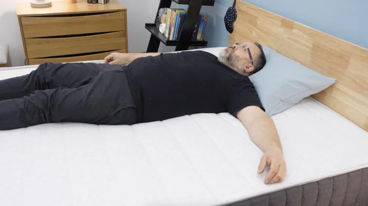 A man lying on his back on the Helix Plus mattress.