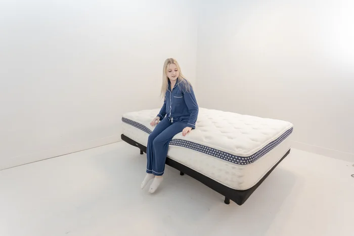 A woman sitting on the edge of the WinkBed mattress.