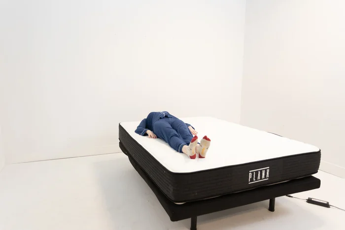 A woman lying on her back on the Plank Firm mattress.