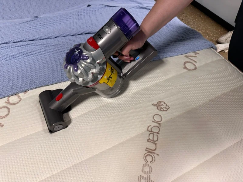 Vacuuming a mattress with a Dyson Car & Boat Handheld Vacuum Cleaner