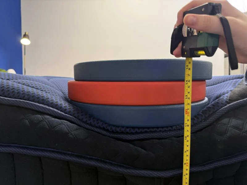 Measuring weight plates on the edge of the DreamCloud Ultra Hybrid Mattress