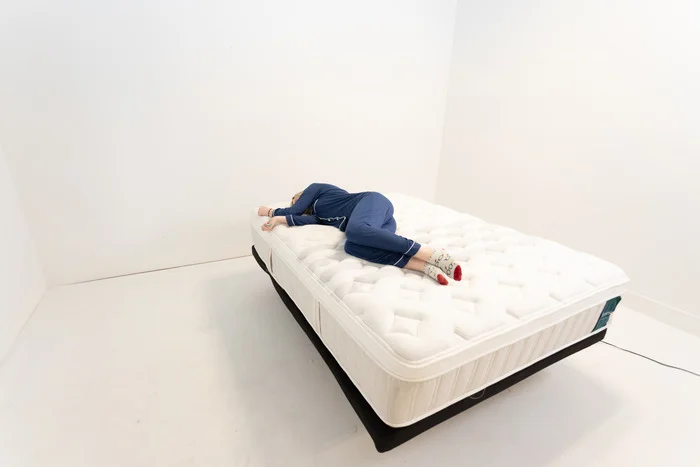 A woman lying on her side on the Leesa Sapira Chill Hybrid mattress.