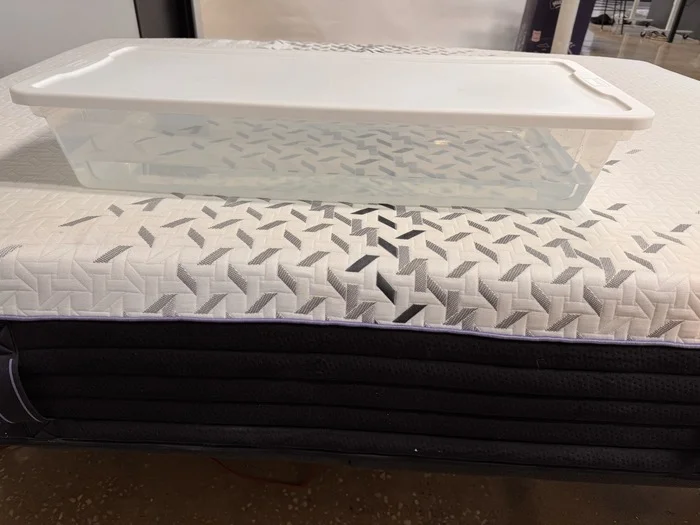 A plastic bin full of water sitting on the Nectar Luxe Hybrid mattress.