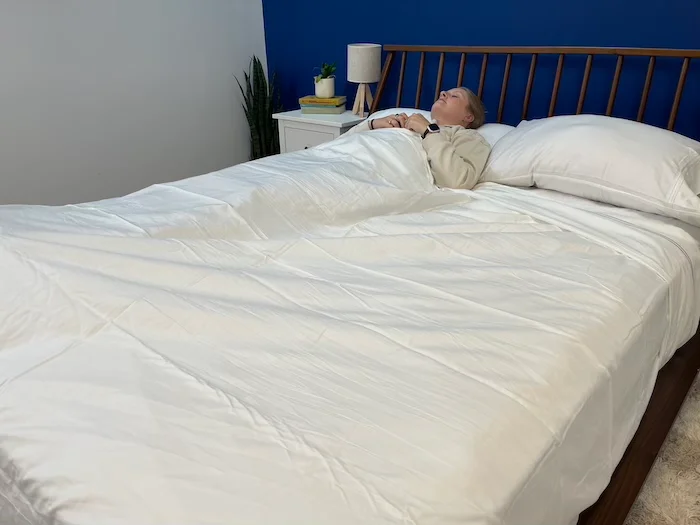A woman sleeping while wrapped in PlushBeds Bamboo Sheets.