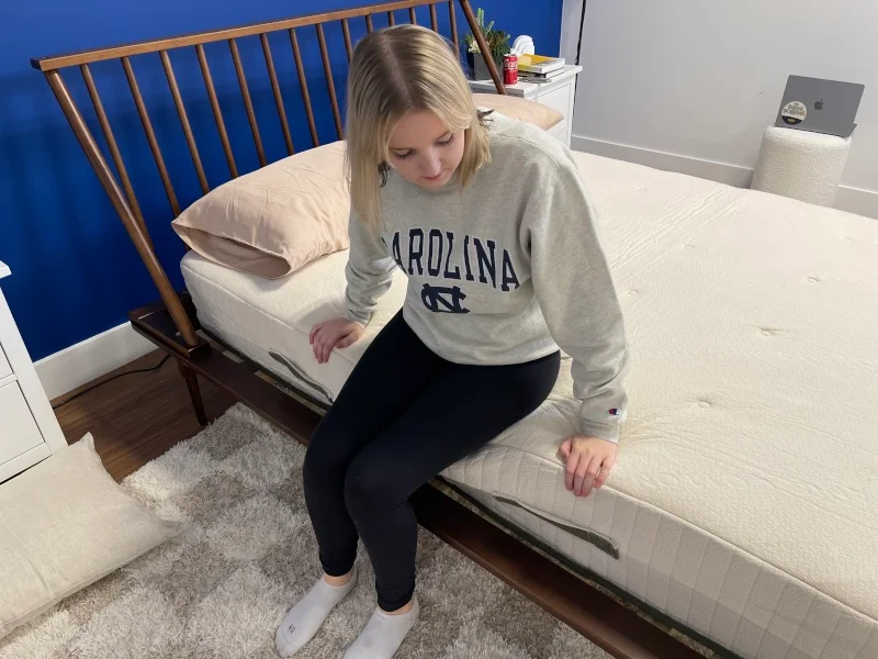 Riley Otis performs a seated edge-support test on an Avocado Eco Organic Mattress