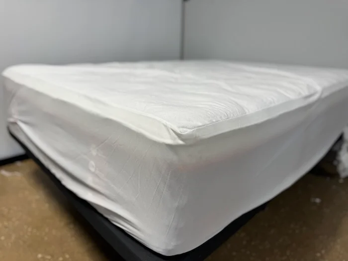 A corner view of the Leesa Mattress Protector stretched tightly over a bed.