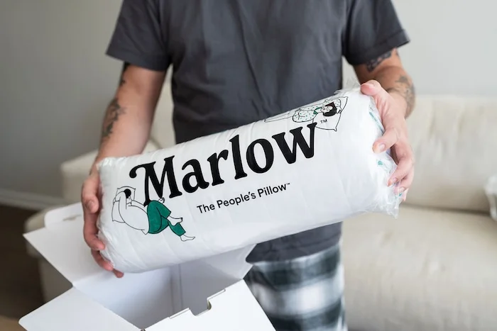 A man holds a Marlow Pillow still in its packaging.