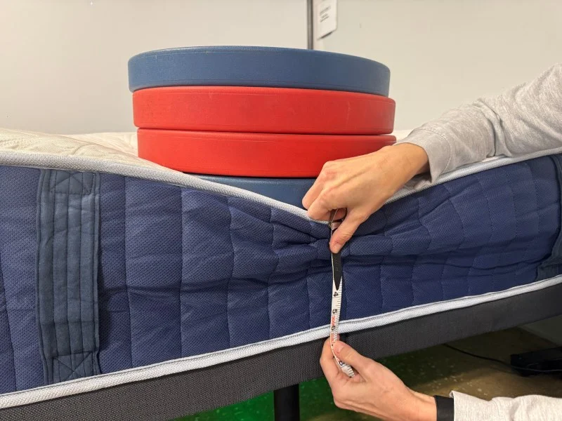 Our tester measuring weight plates on the edge of a Glacier Original Hybrid Mattress