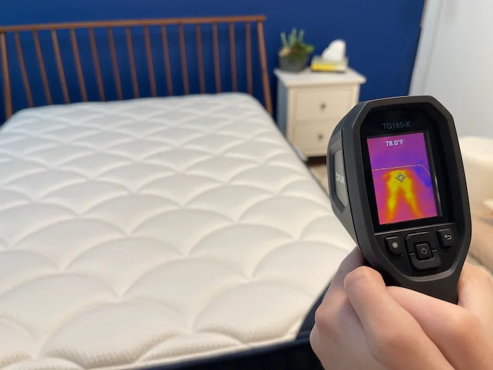 A closeup of someone using a thermal gun to measure the DreamCloud mattress's temperature after someone has rested on it for 5 minutes.