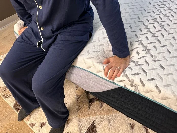 A man sits on the edge of the Nectar Premier mattress