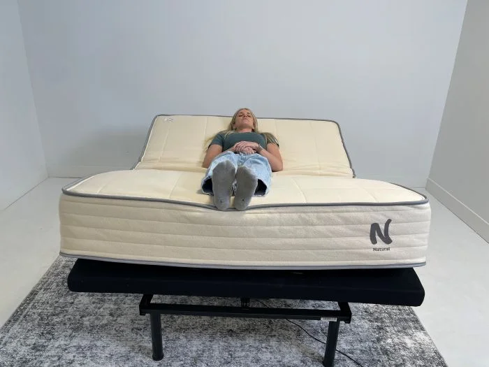 A woman lying on a Nolah Natural mattress while it's on top of an adjustable base.