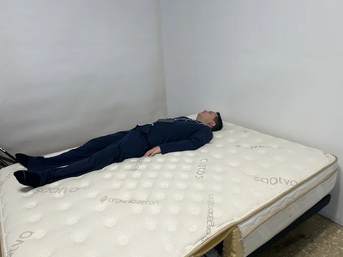 A man lying on his back on the Saatva mattress.
