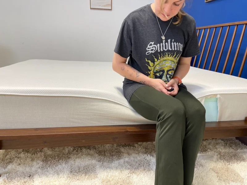Our tester performs a seated edge-support test on a Boring AF Mattress