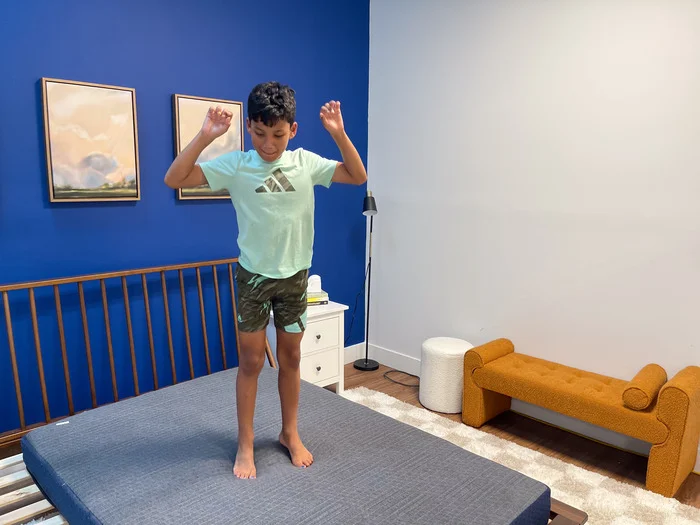 A 10-year-old boy jumping up and down on the BB Kids mattress to test its bounce.