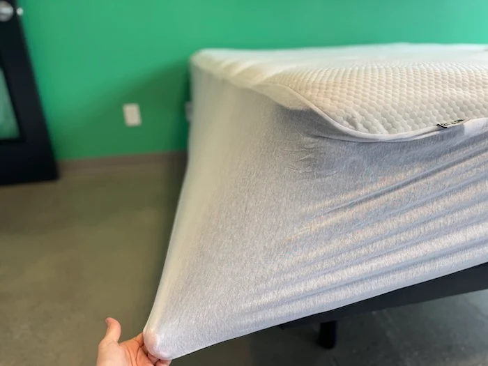 A closeup of a hand pulling on the Bear Mattress Protector to show its snugness.