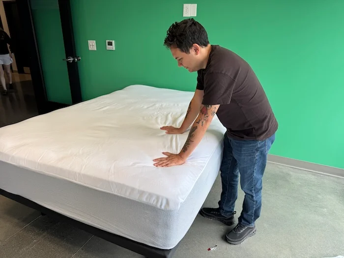 Our tester leans over a freshly-installed Casper Waterproof Mattress Protector