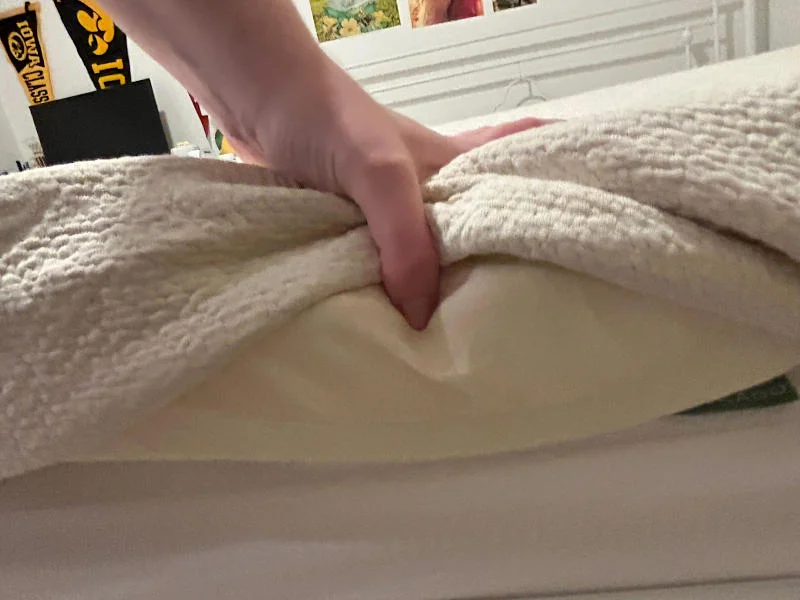 Our tester lifts the cover to show the side of a Avocado Eco Organic Mattress Topper